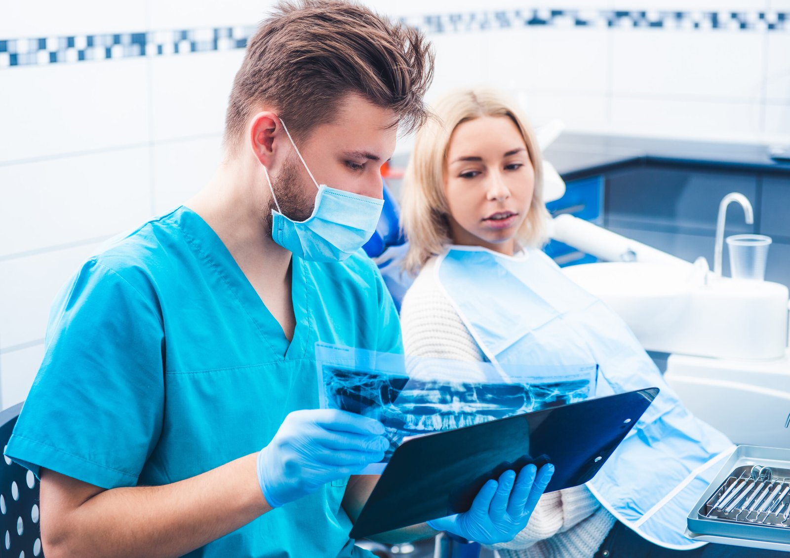 Dentist in mask showing patient dental x-ray